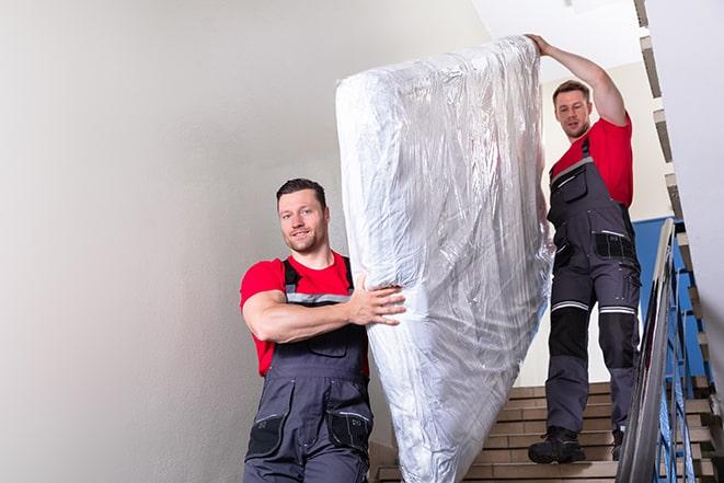 two workers carrying a heavy box spring out of a bedroom in Plainfield